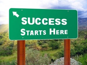 Green road sign that says success starts here